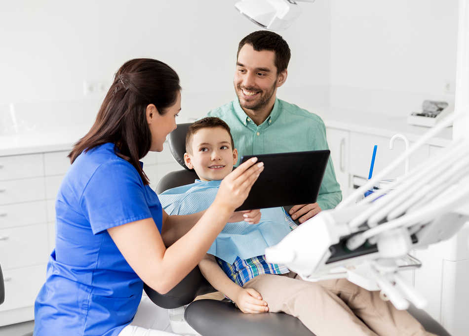Dentist and assistant showing a young patient his X-rays on a tablet